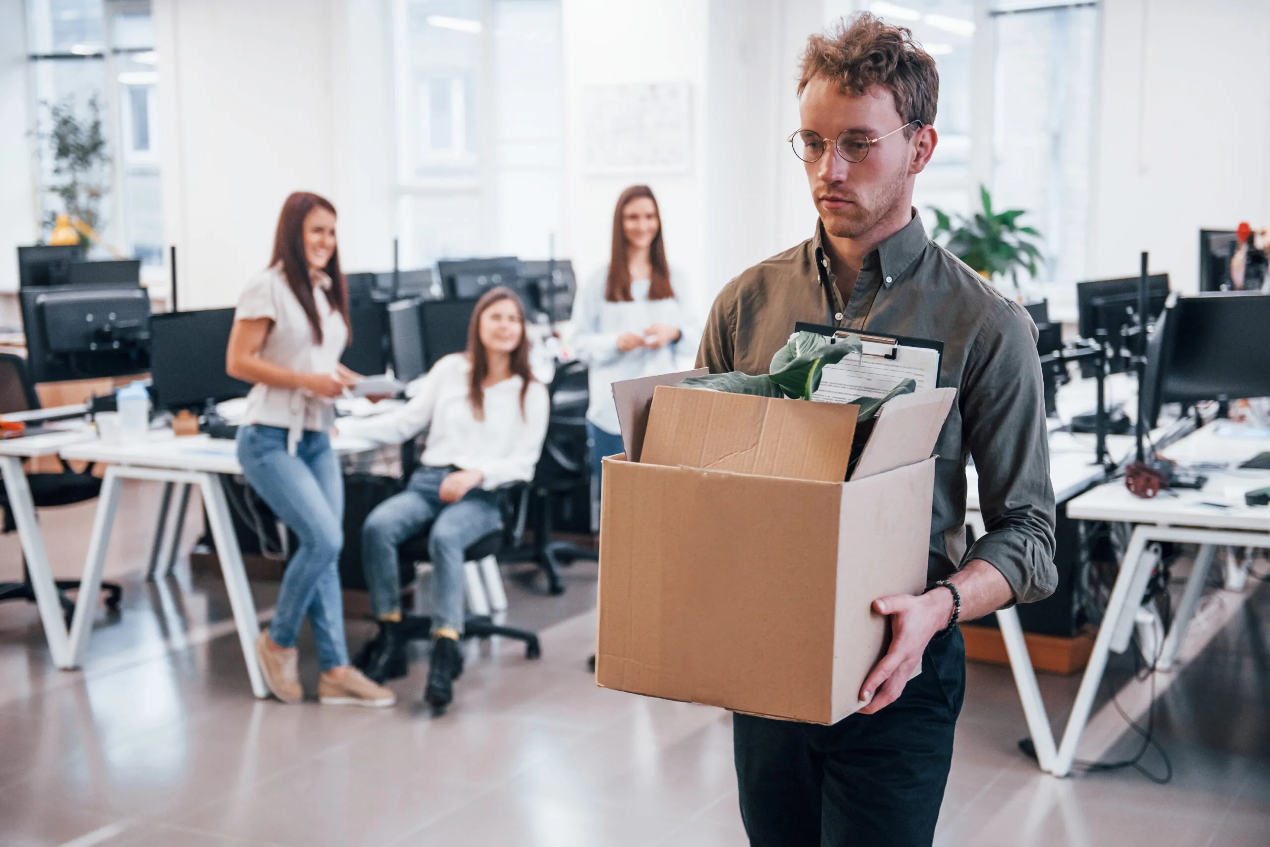 Professional movers loading cardboard boxes into a moving truck while a couple watches outside a residential home.
